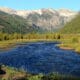 River flowing through a green mountain valley beneath snow-dusted peaks near Telluride, Colorado.