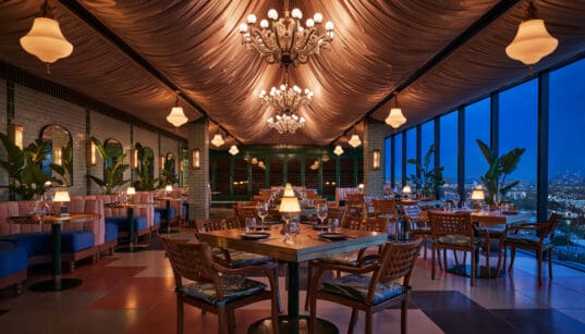Oleander dining room with chandeliers and panoramic Los Angeles views at The Sun Rose West Hollywood.