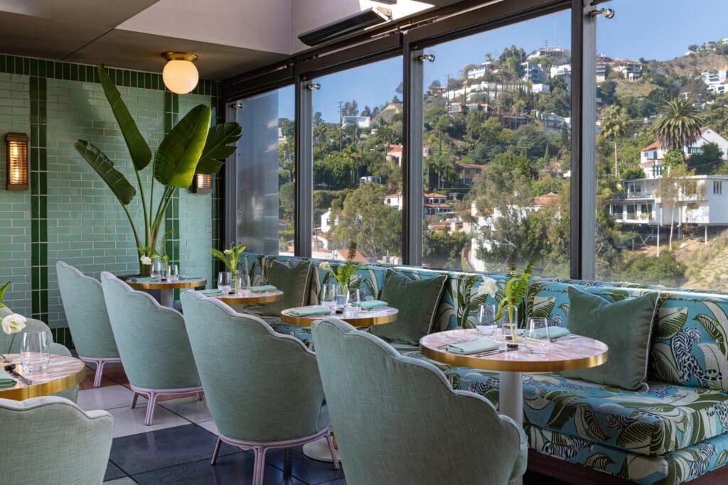 Oleander rooftop restaurant with green seating and Hollywood Hills views at The Sun Rose West Hollywood.