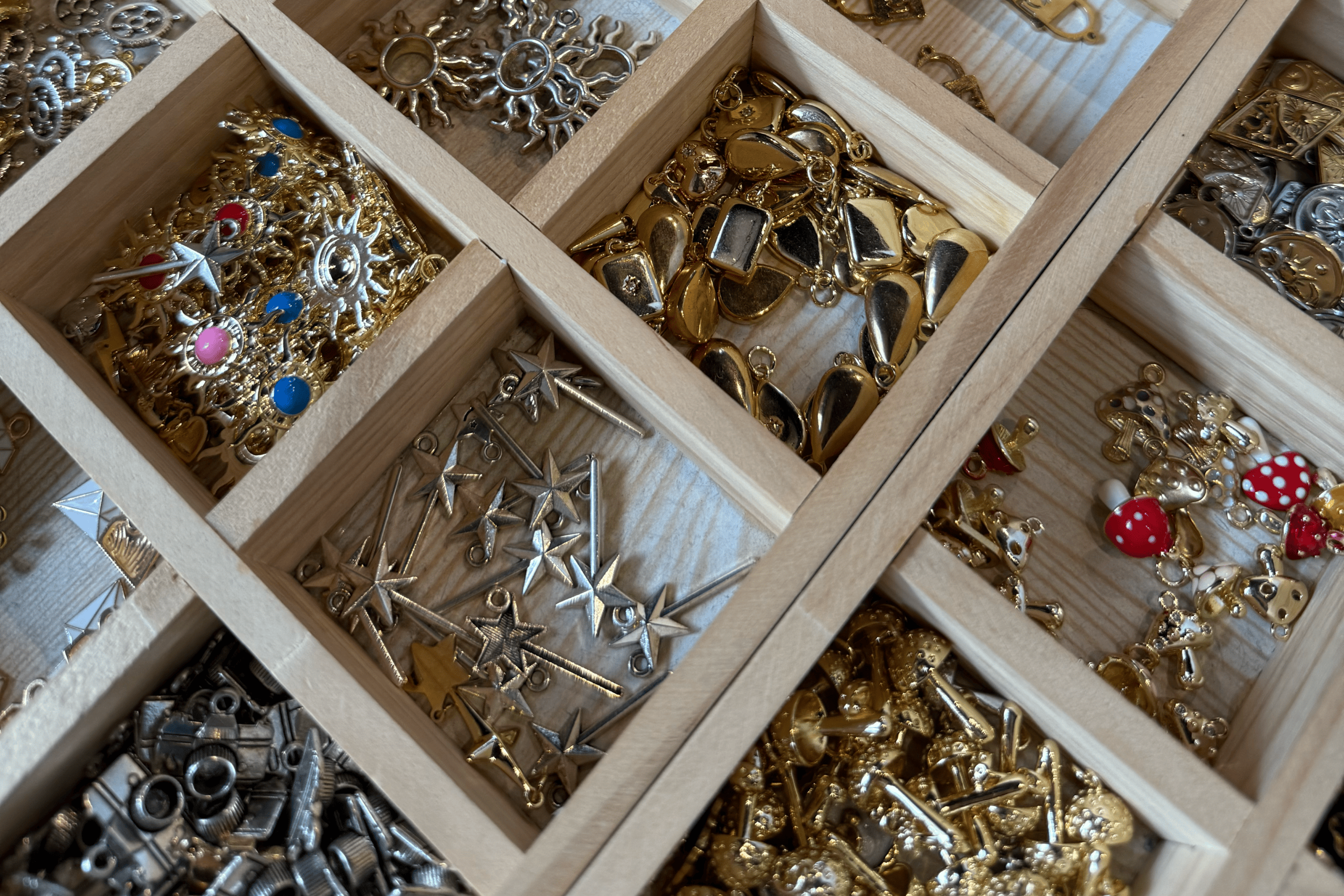 A display tray filled with gold and silver charms for customizing permanent bracelets and necklaces at Chained Up in Denver.