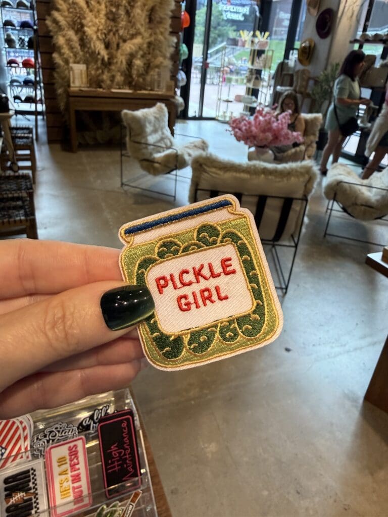 Hand holding a "Pickle Girl" embroidered patch inside Chained Up in Denver.