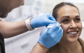 A Facial Aesthetics provider prepares a patient for an injectable treatment near her eye.