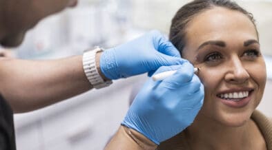 A Facial Aesthetics provider prepares a patient for an injectable treatment near her eye.