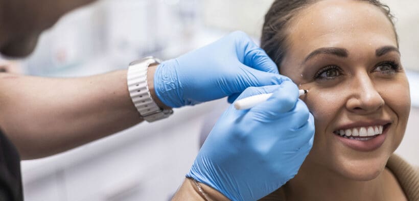 A Facial Aesthetics provider prepares a patient for an injectable treatment near her eye.