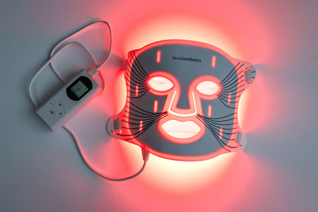 Illuminated red-light therapy face mask and controller used for skincare treatments at Facial Aesthetics.