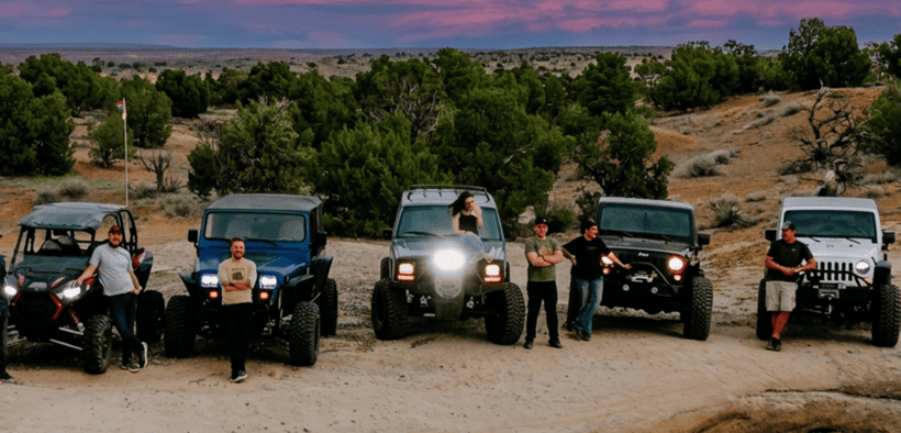 Off-road vehicles and drivers gather on rocky terrain beneath a colorful sunset sky in Farmington, New Mexico.