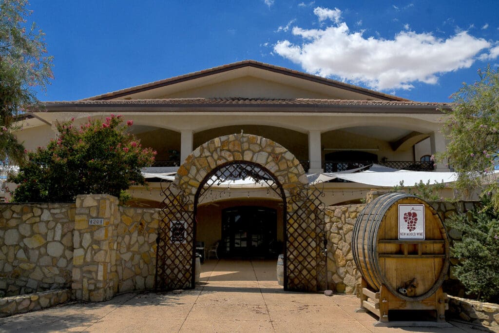 The front of the La Vina Winery in Las Cruces with brick archway and wine barrel. 
