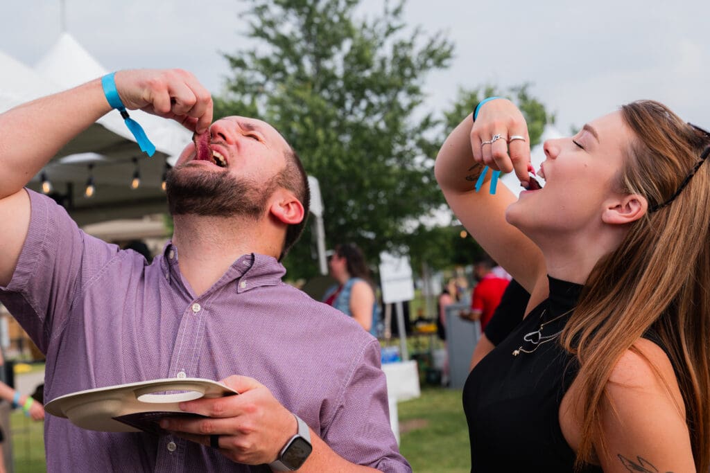 Two guests sampling steak at an outdoor RARE Steak Championship event.