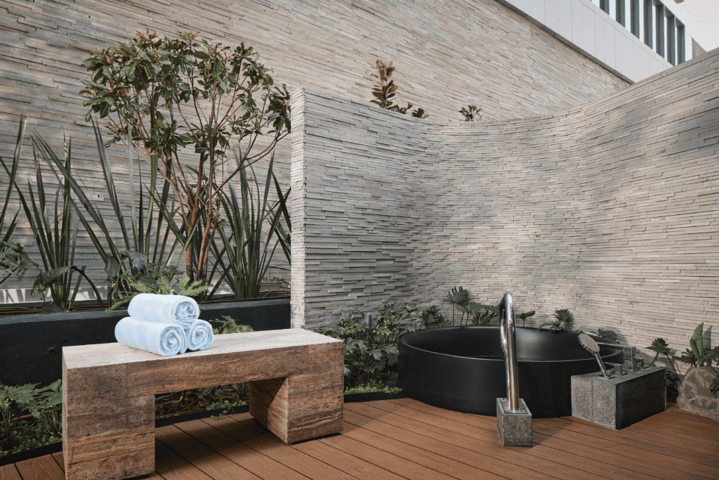 Private outdoor soaking tub surrounded by stone, wood decking and greenery at The St. Regis Mexico City.