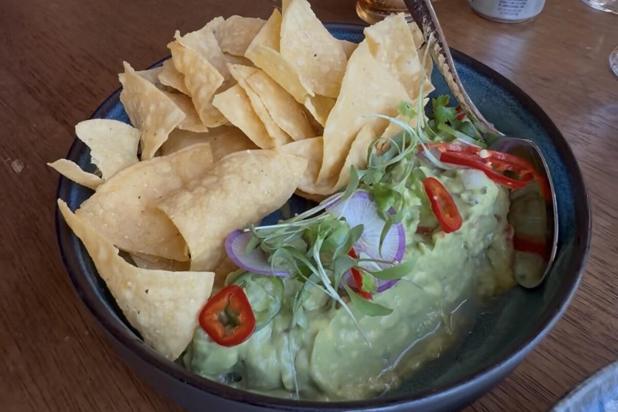 Bowl of traditional guacamole with tortilla chips on a table at Tamayo in Denver.