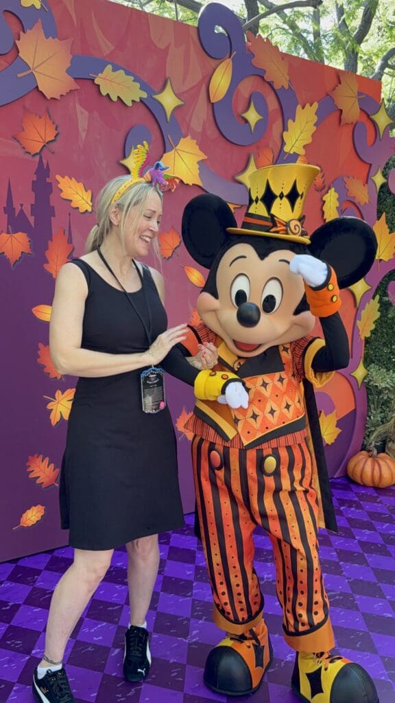 Best of the Southwest founder and editor Erin Thorburn with Mickey Mouse dressed in an orange-and-black Halloween costume at Disneyland Resort.