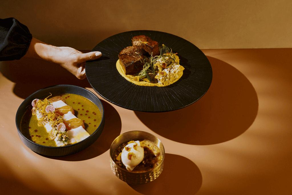 El Sol tasting menu with tiradito, braised short rib and pumpkin crème brûlée arranged in golden light at Tamayo in Denver.