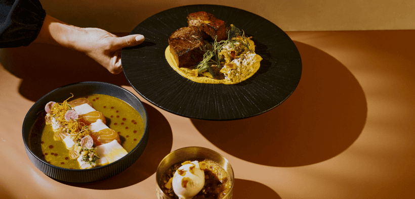 El Sol tasting menu with tiradito, braised short rib and pumpkin crème brûlée arranged in golden light at Tamayo in Denver.
