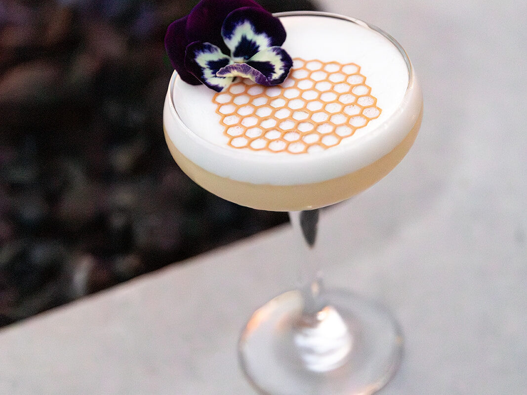 Honey-inspired cocktail topped with a honeycomb design and edible flower at Andaz Scottsdale Resort & Bungalows.