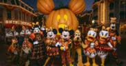 Mickey Mouse and friends in Halloween costumes pose in front of the giant Mickey pumpkin at Disneyland Resort.