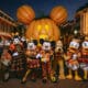 Mickey Mouse and friends in Halloween costumes pose in front of the giant Mickey pumpkin at Disneyland Resort.