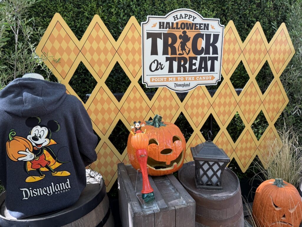 Disneyland Halloween Trick or Treat display featuring a Mickey Mouse sweatshirt, pumpkin decor and Mickey souvenir sipper.