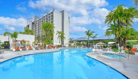 Outdoor swimming pool and hot tub surrounded by palm trees at Hilton Irvine in Orange County, California.