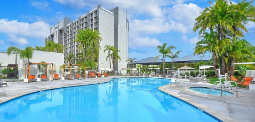 Outdoor swimming pool and hot tub surrounded by palm trees at Hilton Irvine in Orange County, California.