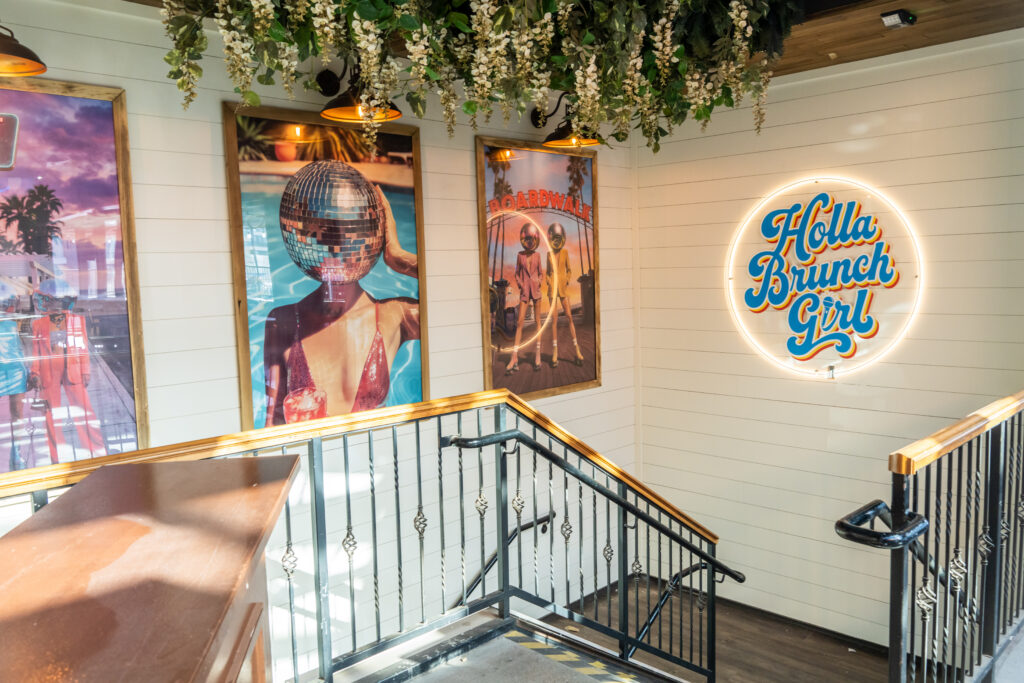 Holla Brunch Girl sign, hanging greenery and retro artwork inside the Old Town Scottsdale brunch venue.