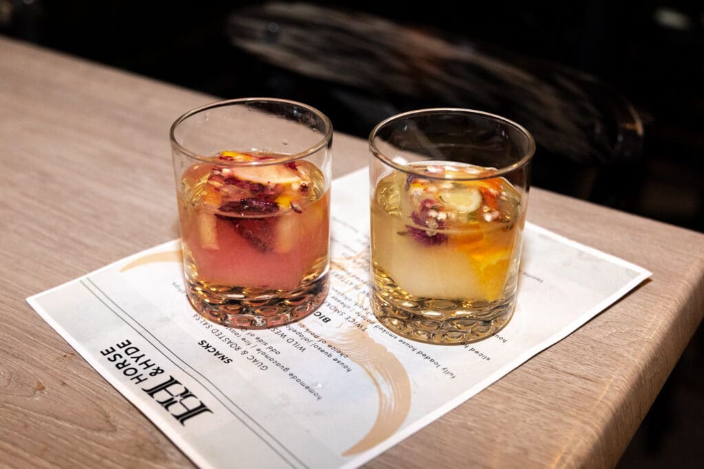 Two cocktails with floral ice cubes served on a Horse & Hyde menu in Phoenix.