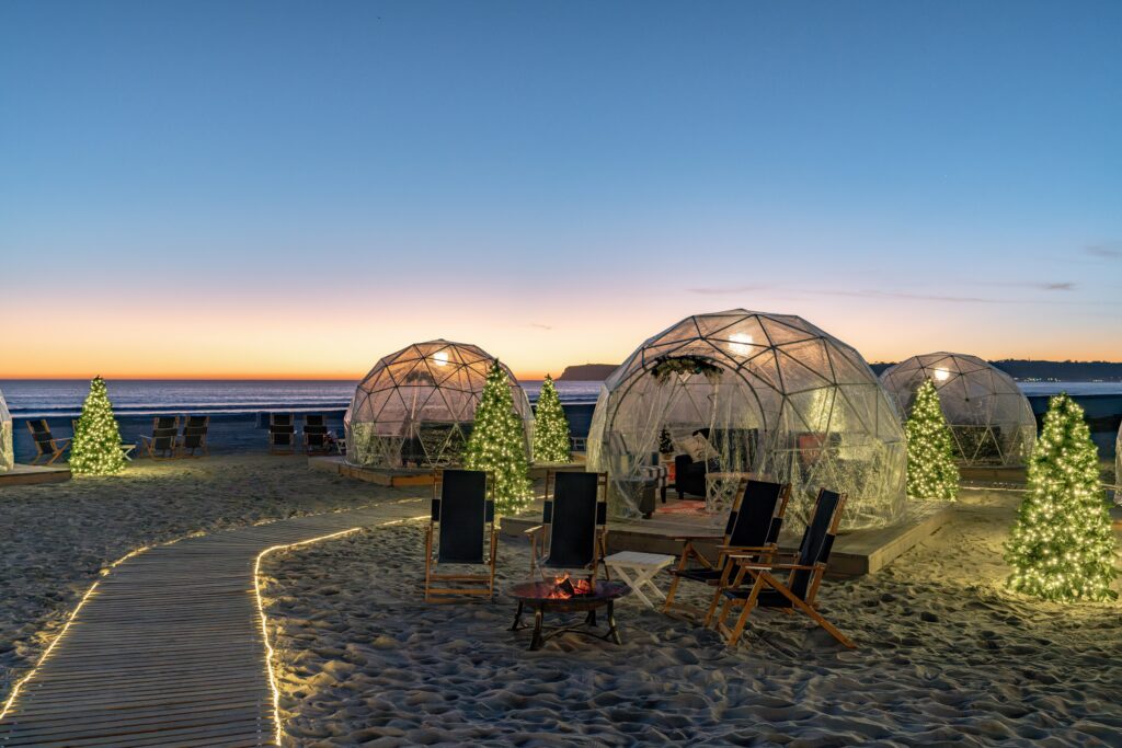 Beachside Igloos and illuminated Christmas trees at sunset on the beach at Hotel del Coronado.