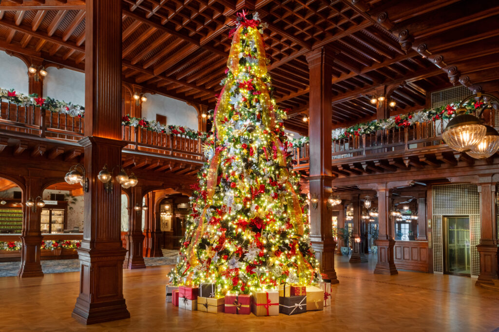 Two-story Christmas tree decorated with lights and ornaments inside the historic Hotel del Coronado lobby.