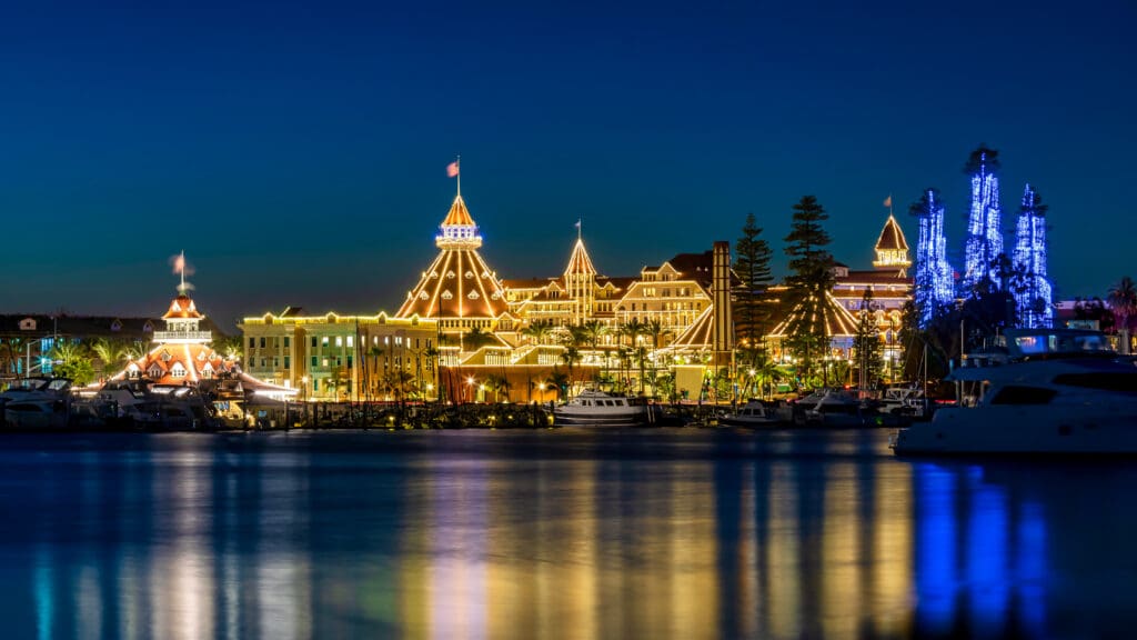 Hotel del Coronado illuminated with holiday lights at night along the Coronado waterfront.