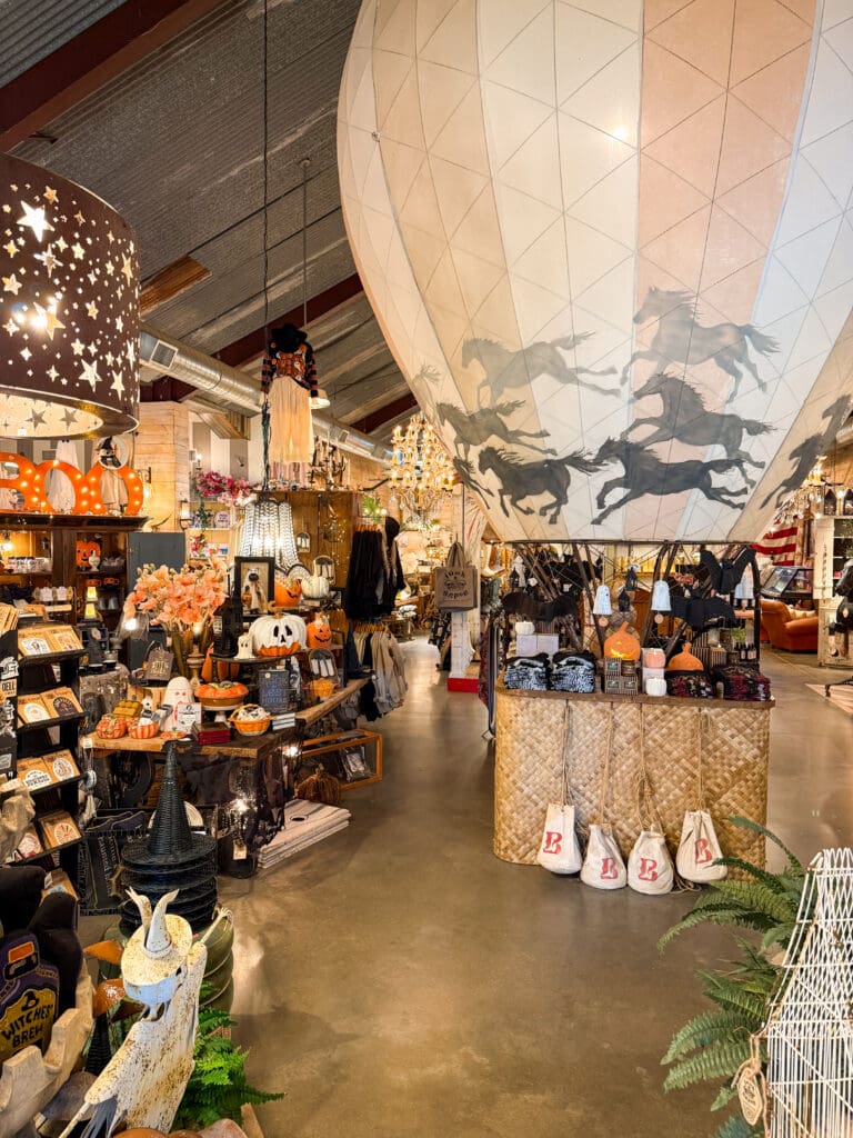 Colorful interior of Junk Gypsy in Round Top with a large horse-themed balloon, Halloween displays, clothing and home décor.