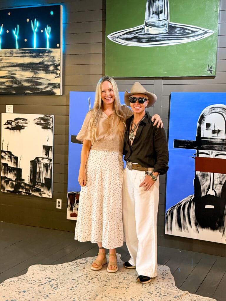 Erin Thorburn and artist Laura Goodson standing together among large-scale Western artwork at Laura Goodson Art in Round Top, Texas.