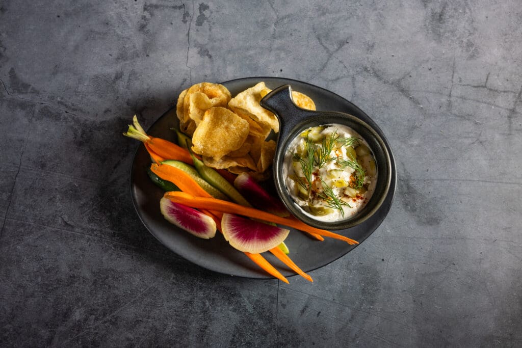 Postino’s Hot Pickle Dip served with house chips, carrots, cucumbers and radishes.