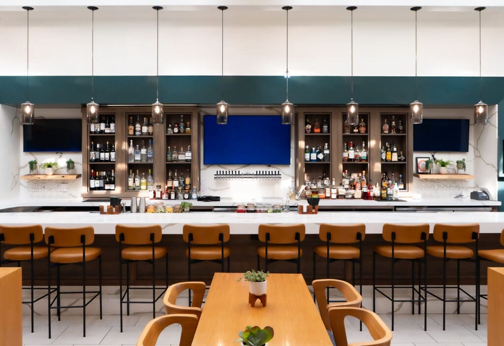 Bar and seating area at Trellis & Tide restaurant inside Hilton Irvine.