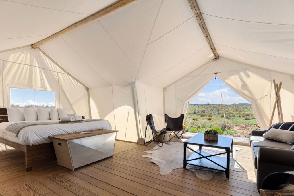 Spacious Under Canvas suite tent with a king-size bed, lounge furniture and an open view of the landscape
