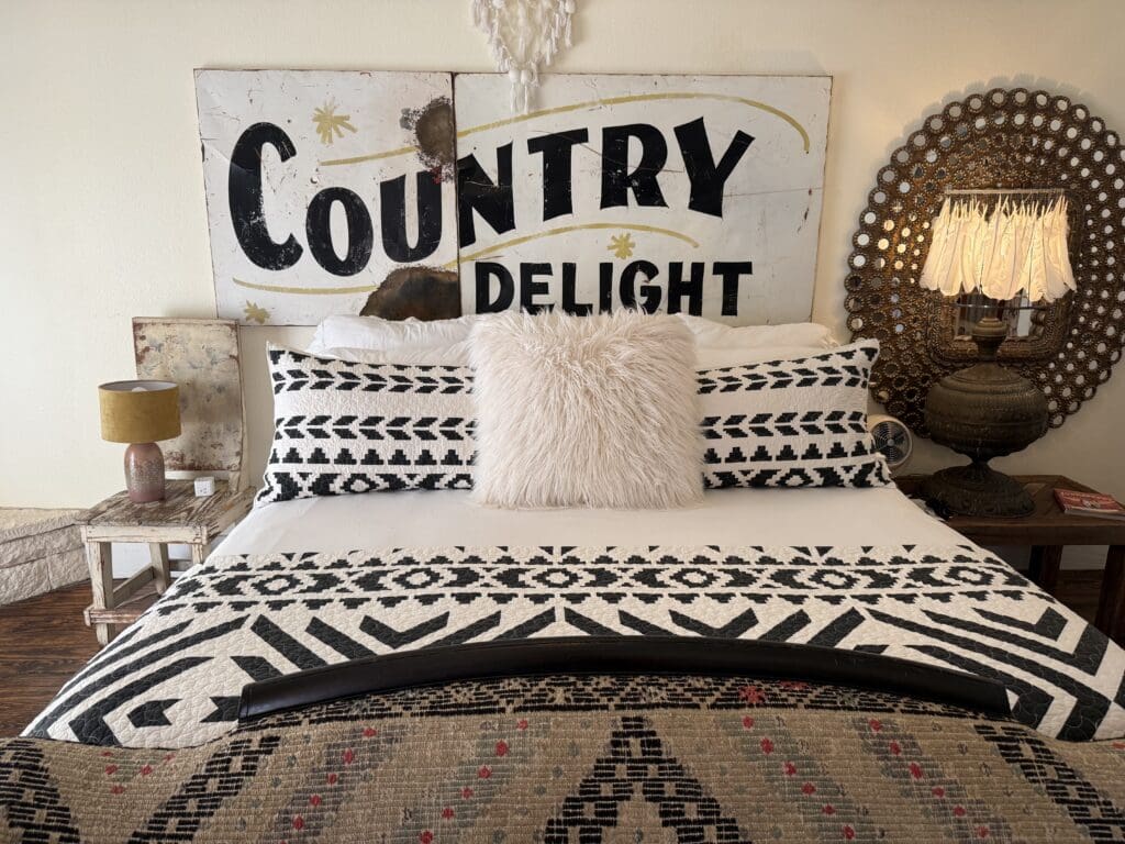 Wander Inn guest room in Round Top with a bed, vintage settee, cowhide rug, fireplace and French doors.