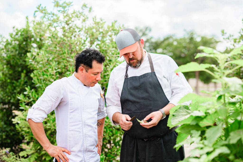 A chef stands next to chef David Rule to examine fresh produce growing in a garden at Millie Leigh’s in Midland, Texas.