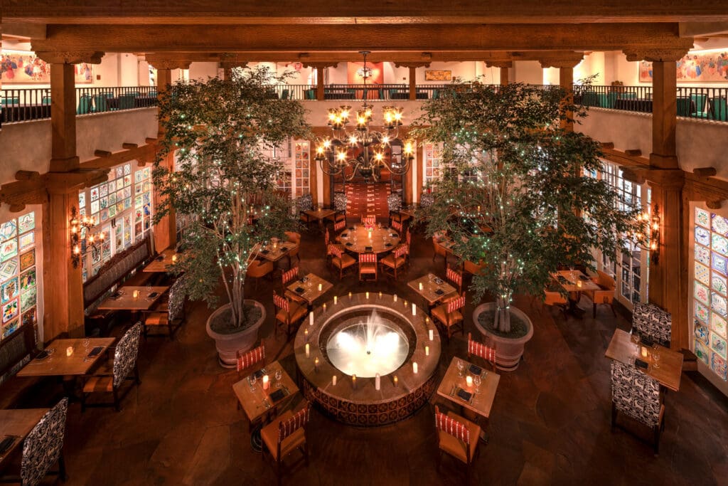 La Plazuela dining room with a central fountain, trees and Southwestern architecture in Santa Fe.