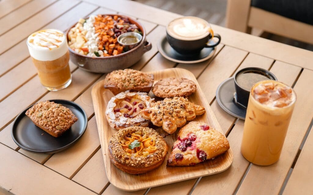 Seasonal pastries, specialty coffee drinks and a harvest-inspired bowl arranged on a wooden table at Buzz & Bustle in Dallas.