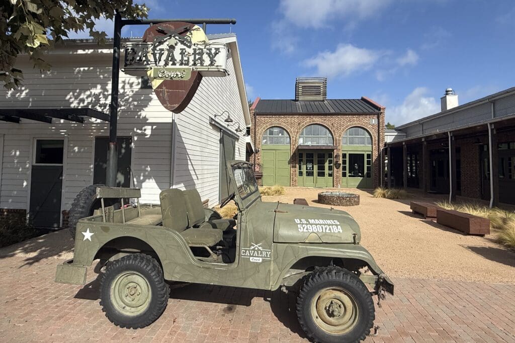 Vintage olive-green military-style Jeep parked in the courtyard of Cavalry Court hotel in College Station, Texas.