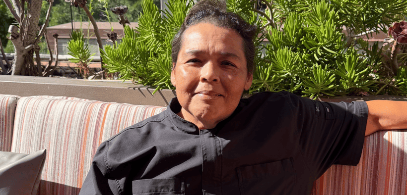Chef Linda Garcia seated on the rooftop terrace at Topside Terrace Kitchen & Bar in San Diego