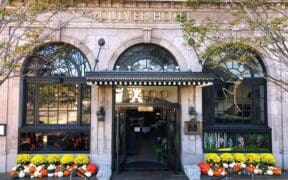 The Culver Hotel façade decorated with skeletons, orange and white pumpkins and yellow flowers around the entrance.