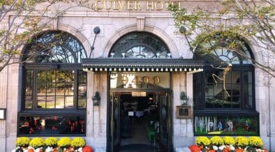 The Culver Hotel façade decorated with skeletons, orange and white pumpkins and yellow flowers around the entrance.