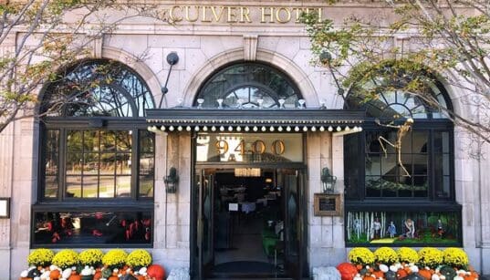 The Culver Hotel façade decorated with skeletons, orange and white pumpkins and yellow flowers around the entrance.
