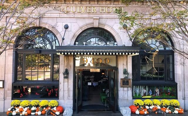 The Culver Hotel façade decorated with skeletons, orange and white pumpkins and yellow flowers around the entrance.