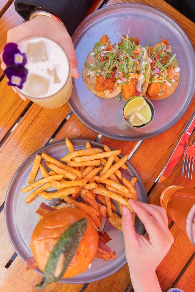 Tacos, burger, fries and drinks served on an outdoor table at Topside Terrace in San Diego.