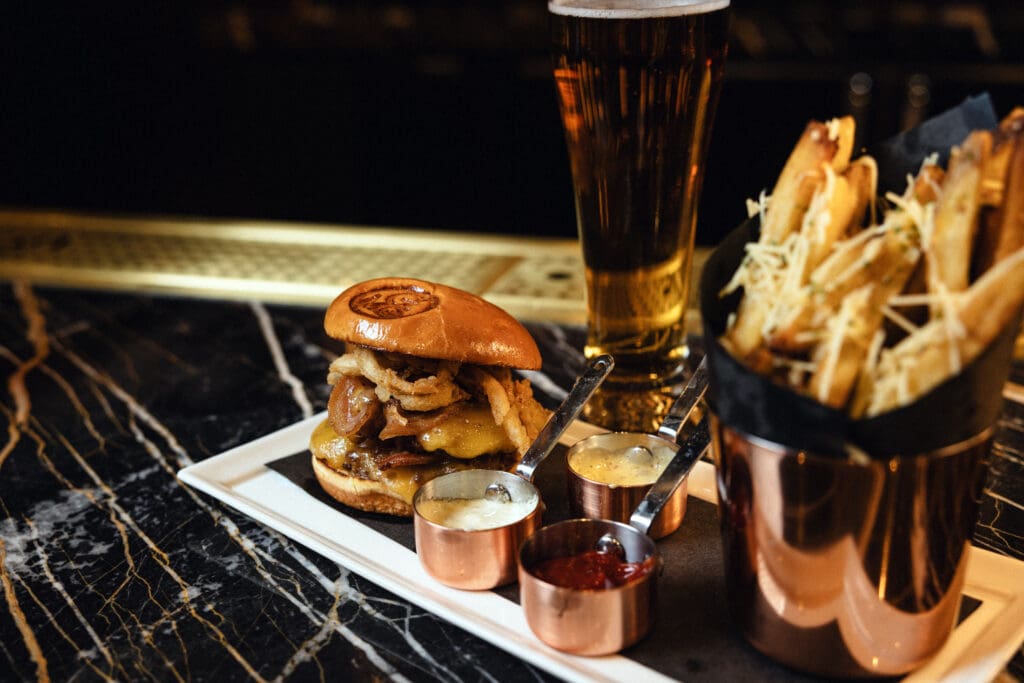 Cheeseburger topped with fried onions and served with fries at Gregory’s Mesquite Grill.