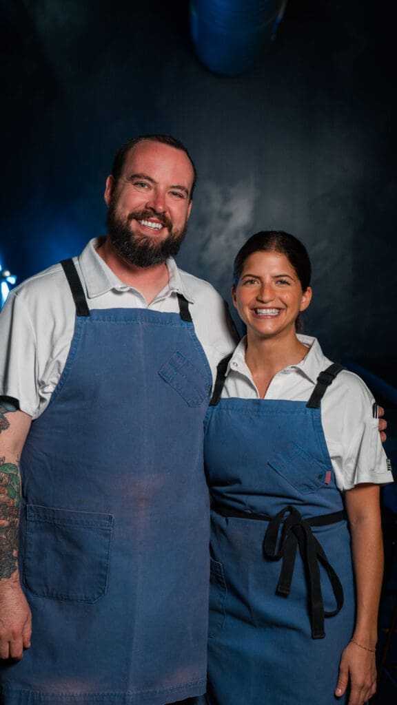 Chefs Harrison Porter and Rema Maaliki wearing blue aprons at BearLeek in Denver.