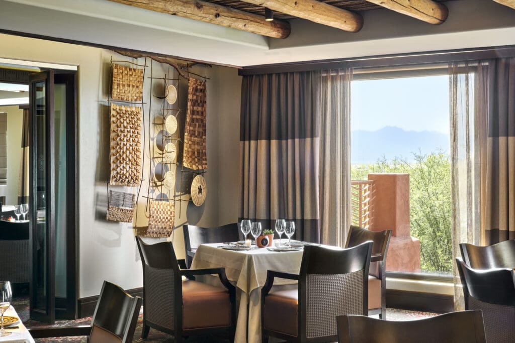 Kai dining room with white tablecloths, woven artwork and a view of the Sonoran Desert.