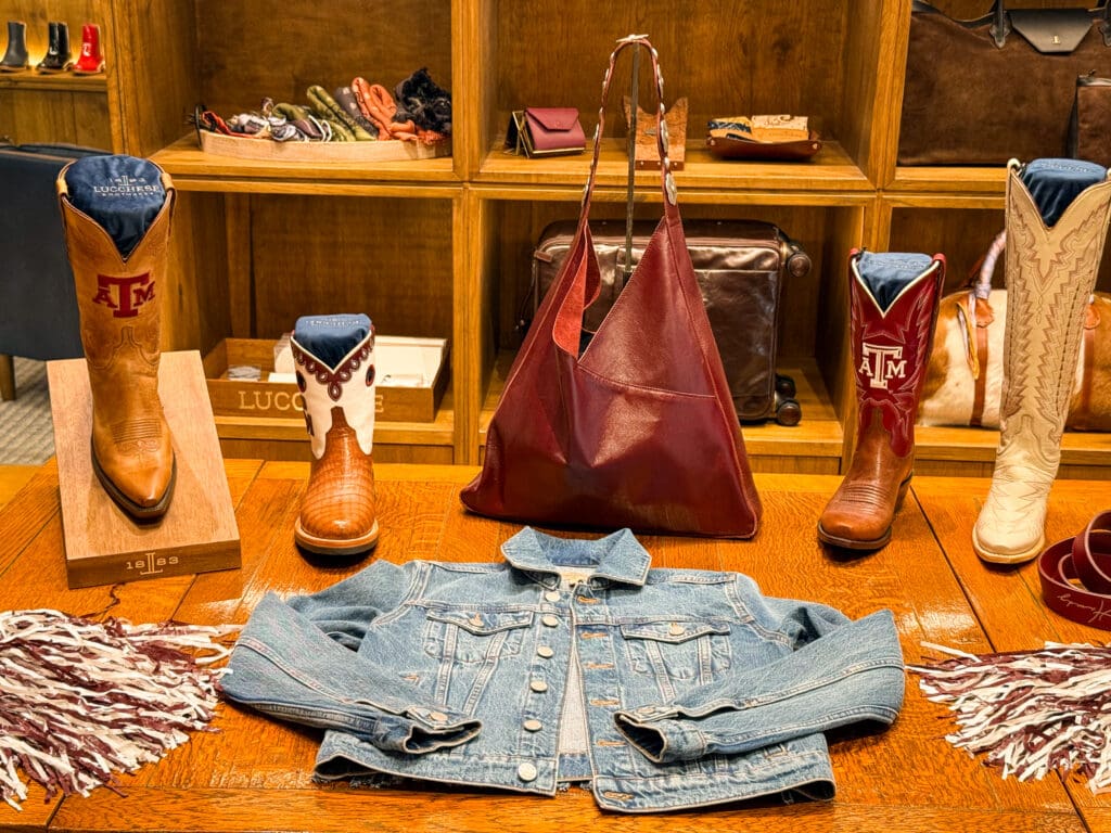 Texas A&M-themed Lucchese cowboy boots displayed with leather accessories and a denim jacket in College Station.
