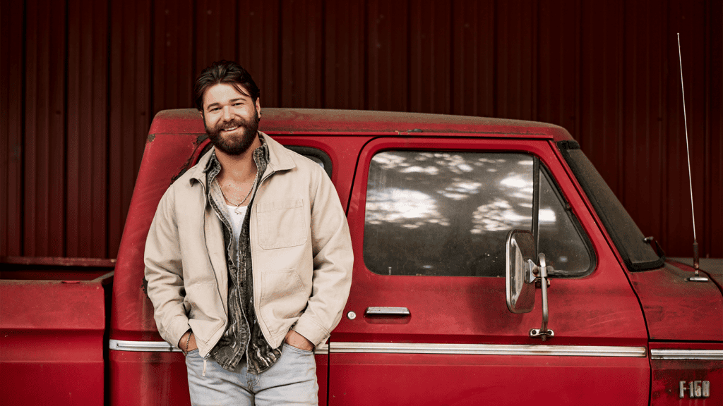 Country music artist McCoy Moore standing in front of a vintage red pickup truck.