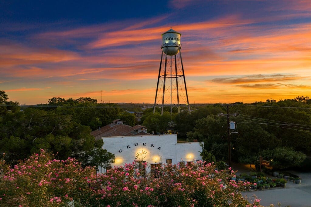 Gruene Hall and Gruene water tower beneath a colorful sunset in New Braunfels, Texas.
